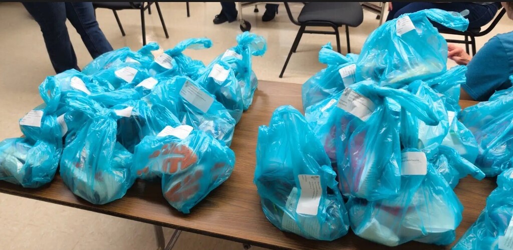 Big blue bags of shoes on a table together.