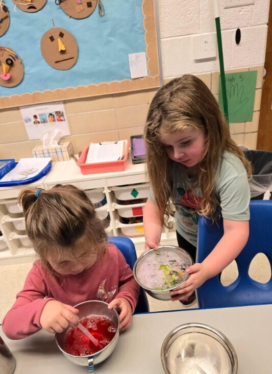 Two girls making a potion project together at a table.