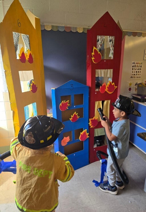 Two preschool boys making a pretend fire scene.