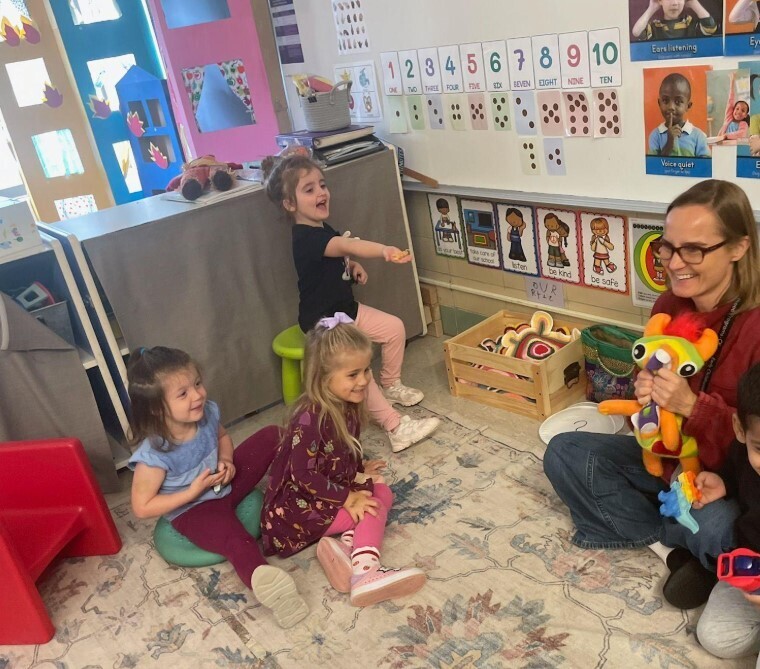 Students laughing together while playing with puppets.