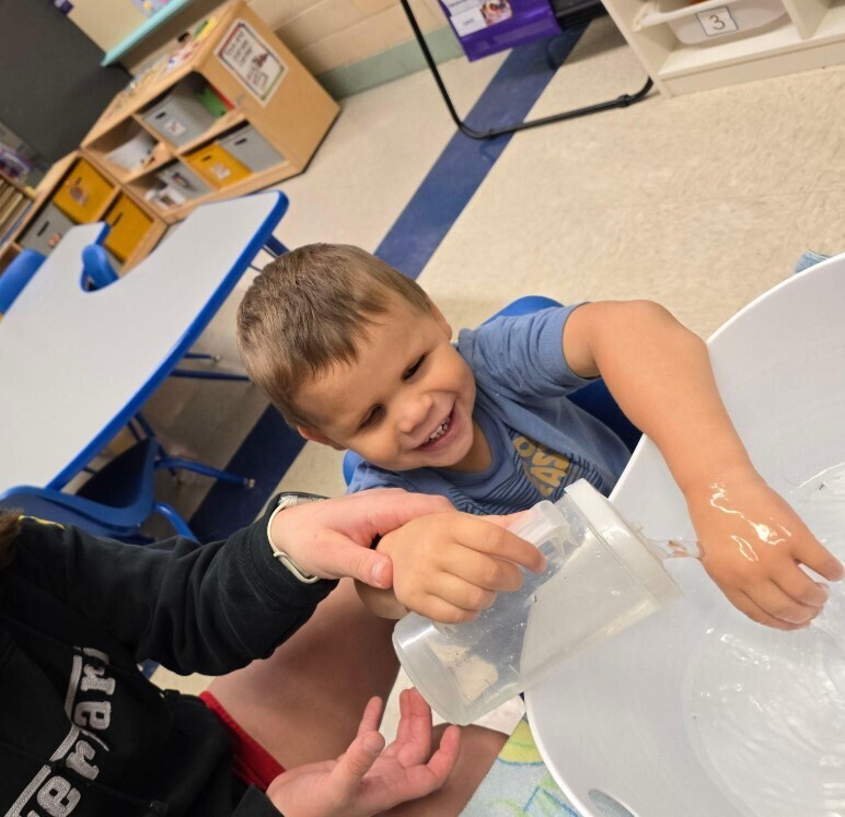 A little boy playing in a water bowl.