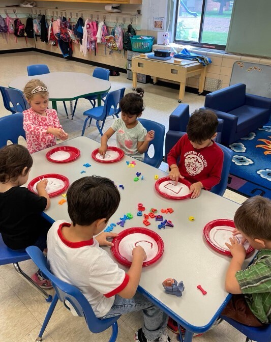 A grou p of preschoolers drawing the letter C on their paperplates.