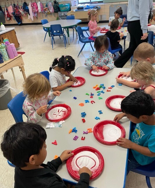 A group of preschoolers filling in their paperplates with markers and paint.