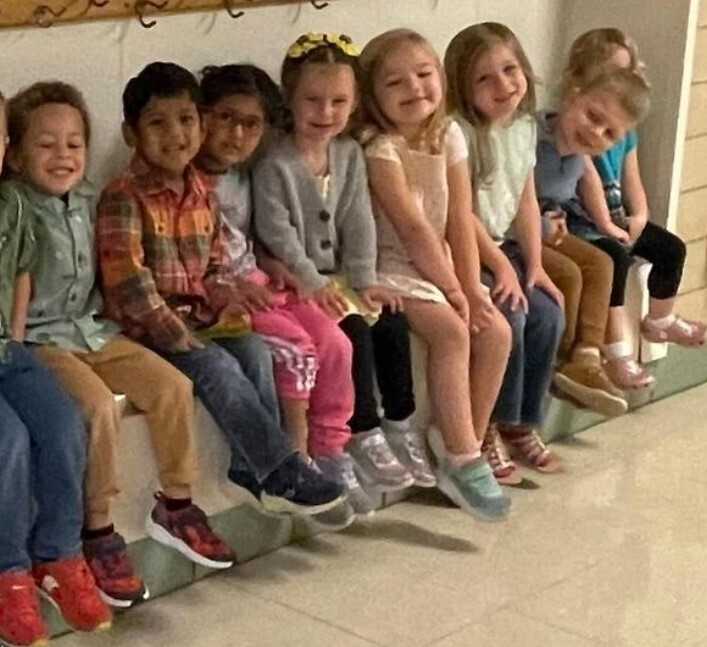 A group of students sitting in the hallway waiting to have their picture taken together.