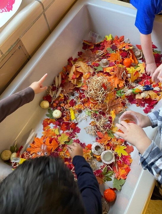 A fall sensory bin with many colors of leaves.