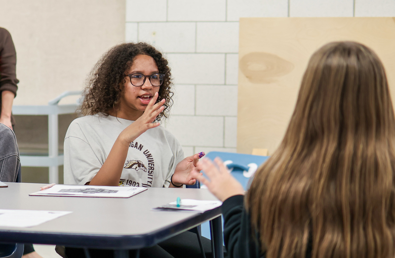 a girl speaking sitting a table