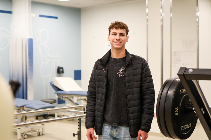 a boy standing in a rehab therapy classroom posing for a photo