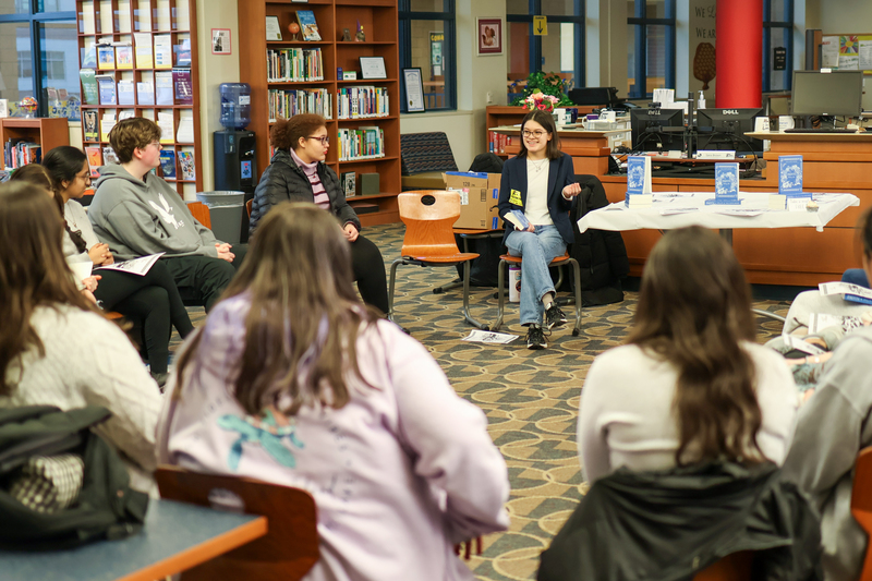 a woman sitting in a circle of people in a library