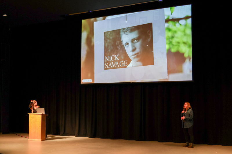 a screen with a photo of Nick Savage is displayed in the auditorium