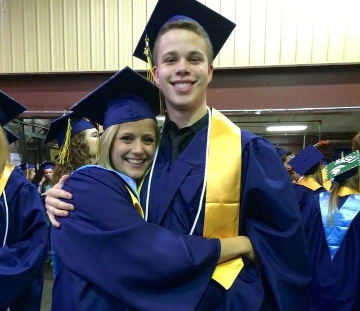 two high school graduates pose for a photo hugging