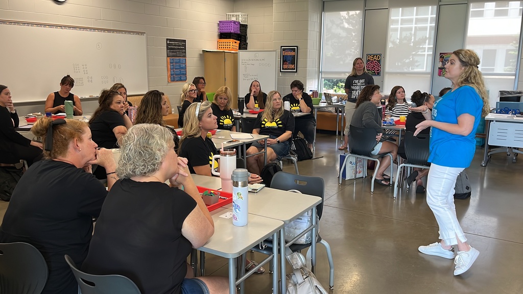 Staff members sitting at tables listen to a speaker as part of a professional development seminar.