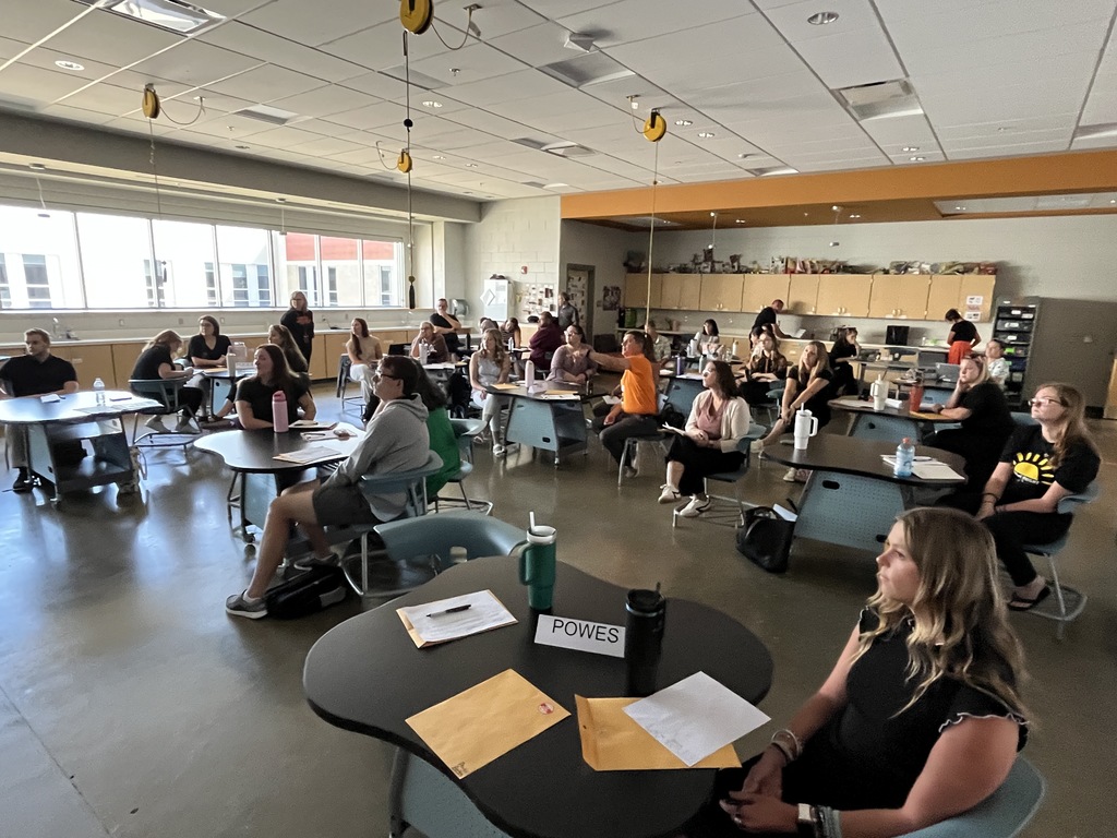 Staff members sitting at tables listen to a speaker as part of a professional development seminar.