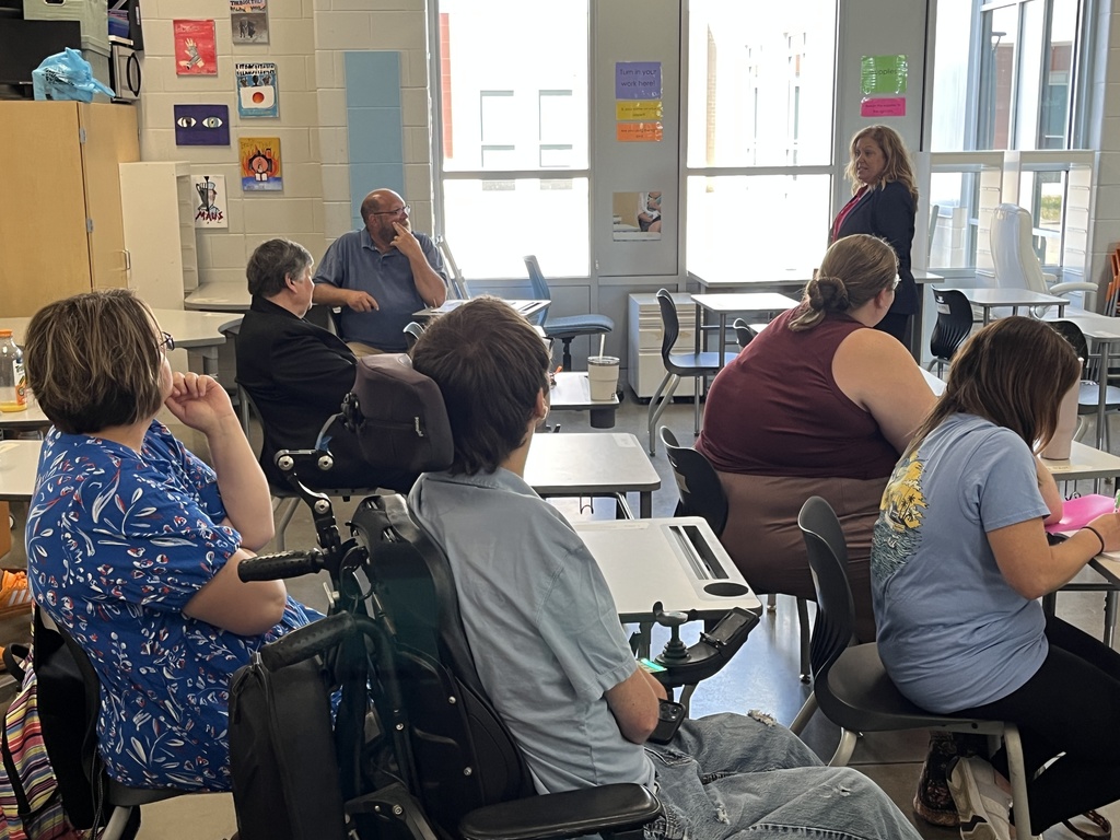 Staff members sitting at tables listen to a speaker as part of a professional development seminar.