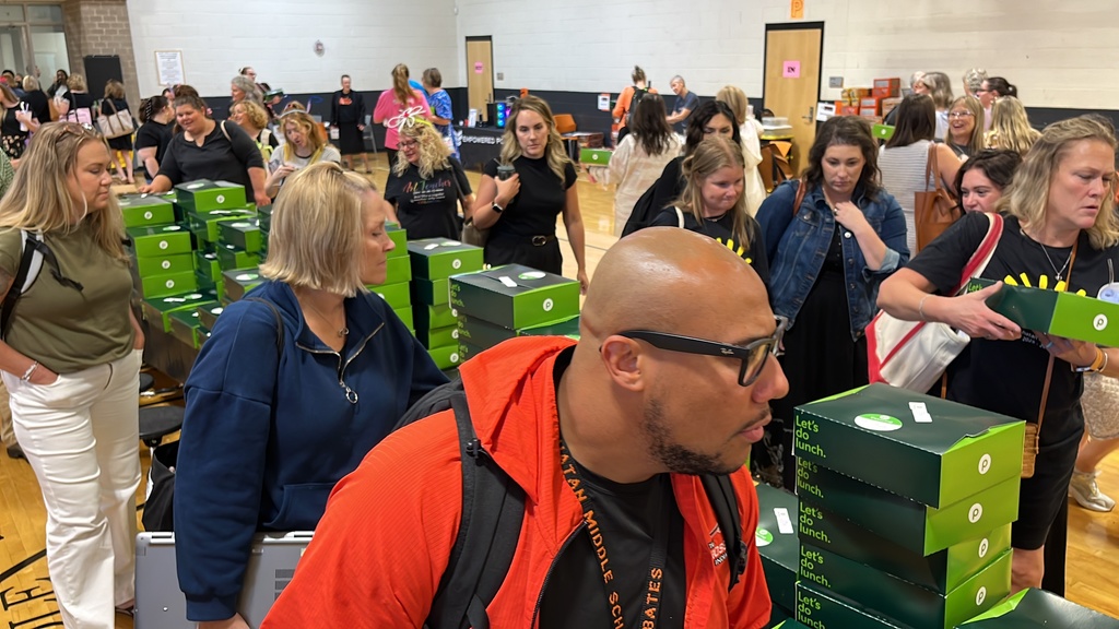 Staff members on either side of a long table choose from boxed lunches. 