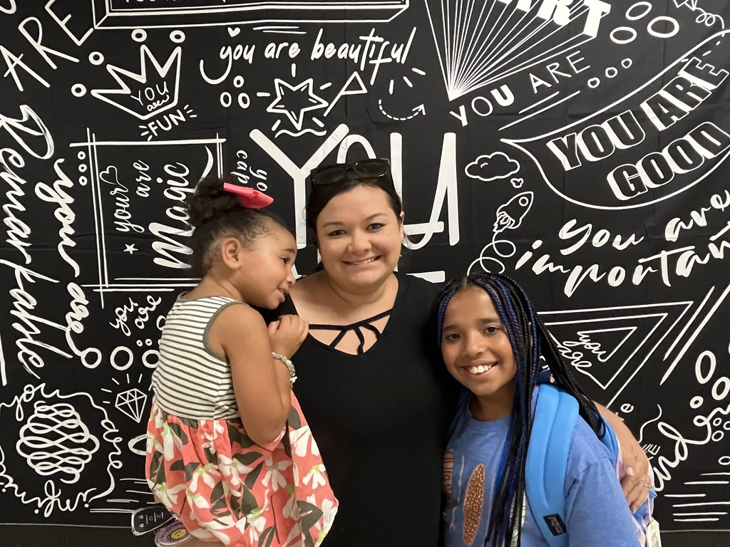 An adult and two children pose for a photo. 