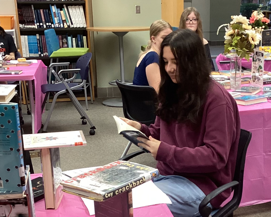 Students sitting at tables full of books participate in a book tasting.  