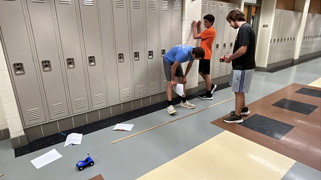 High school physics students conduct an experiment exploring constant velocity using toy cars.