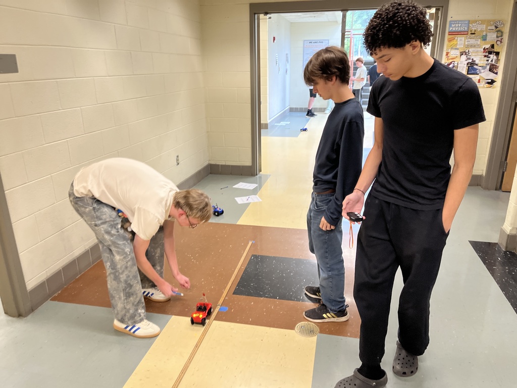 High school physics students conduct an experiment exploring constant velocity using toy cars.