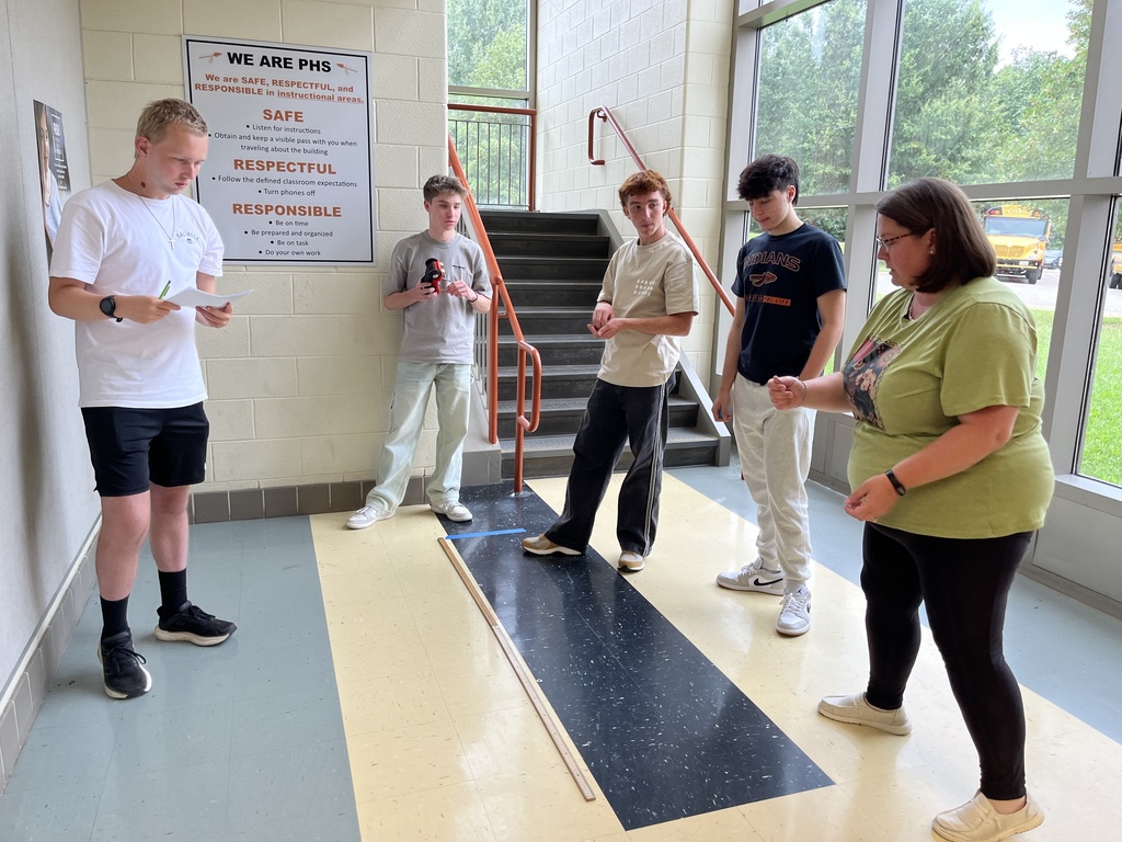 High school physics students conduct an experiment exploring constant velocity using toy cars.