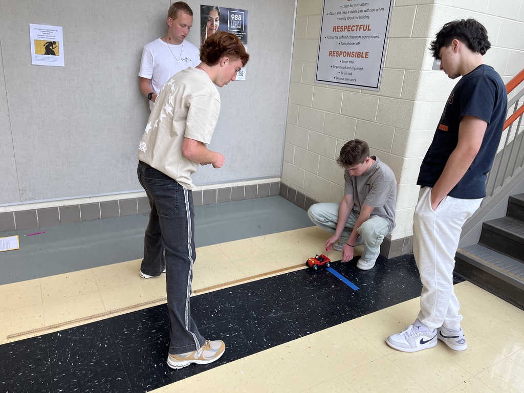 High school physics students conduct an experiment exploring constant velocity using toy cars.
