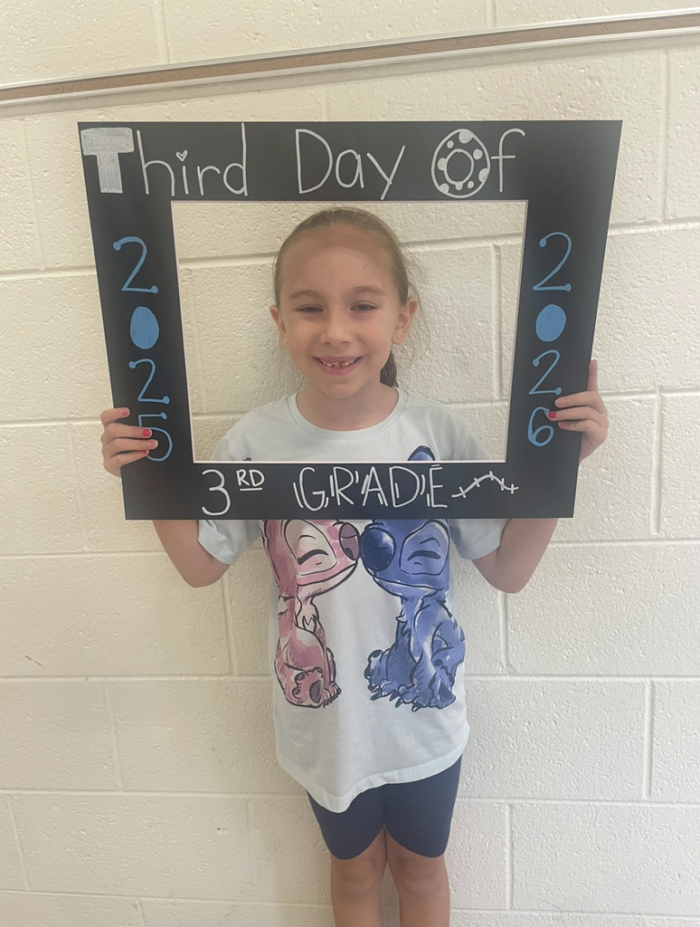 A third grader takes a photo with a photo prop that says Third Day of 3rd Grade 2025-2026.