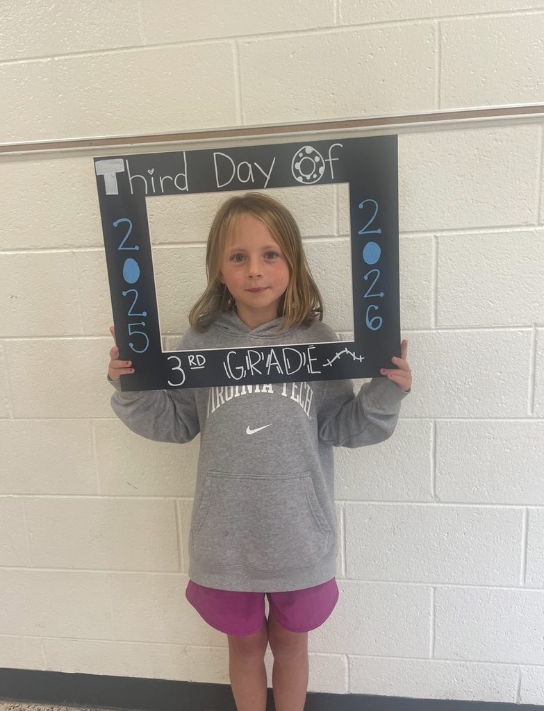 A third grader takes a photo with a photo prop that says Third Day of 3rd Grade 2025-2026.