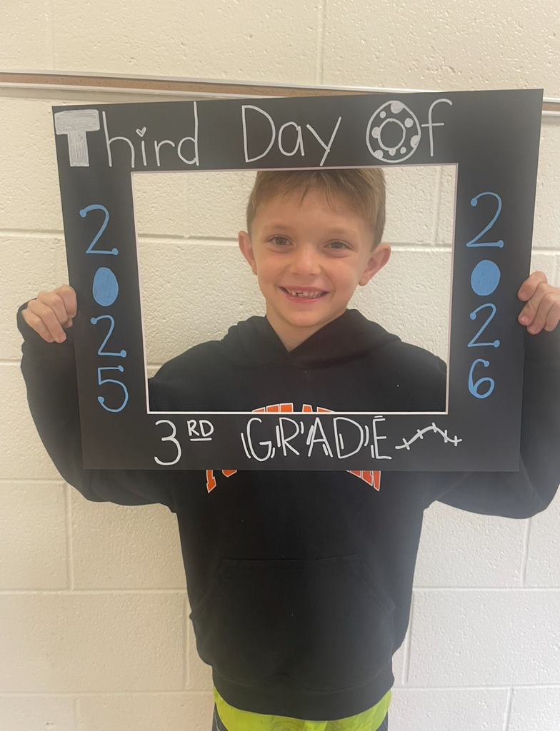 A third grader takes a photo with a photo prop that says Third Day of 3rd Grade 2025-2026.