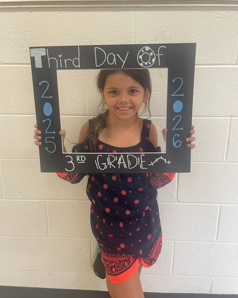 A third grader takes a photo with a photo prop that says Third Day of 3rd Grade 2025-2026.
