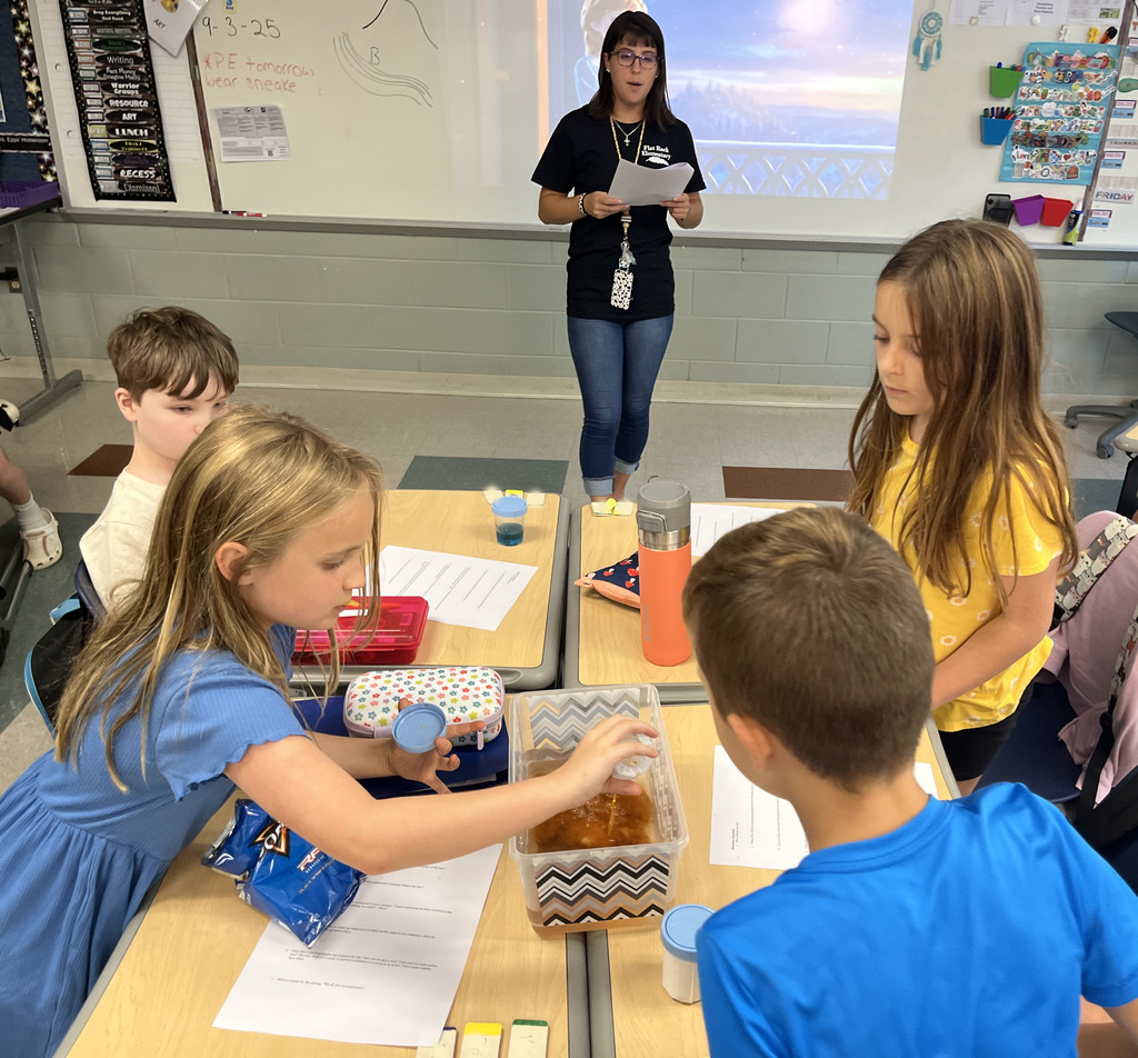 Students observe the impact pollutants have on water during an experiment following directions from a teacher. 