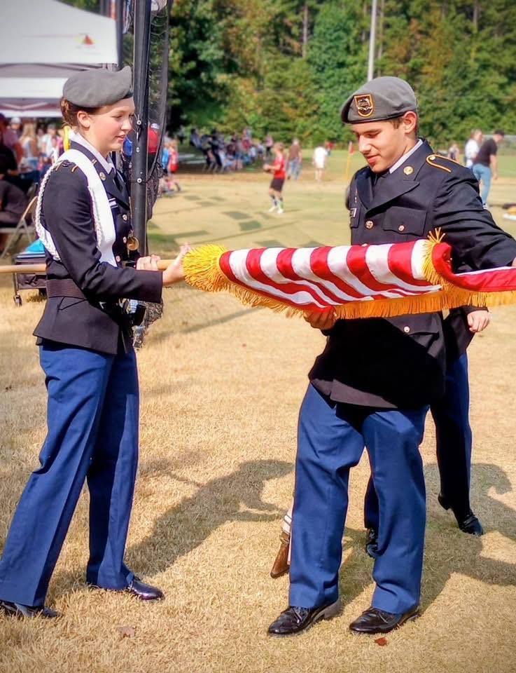 JROTC cadets put away a flag after presenting  the Colors.