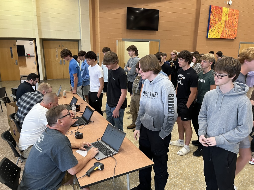 Students check in with staff members to receive their Chromebooks. 