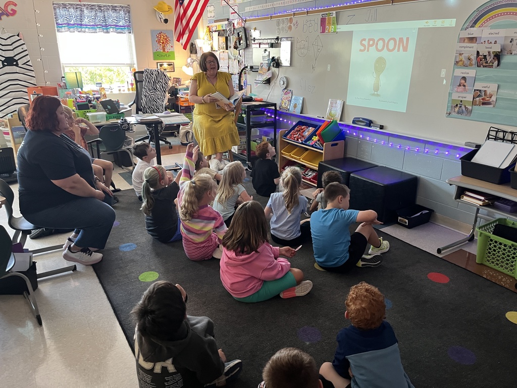 A teacher reads a book to a group of students. 