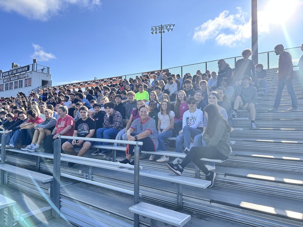 Outdoor bleachers are filled with students and teachers. 