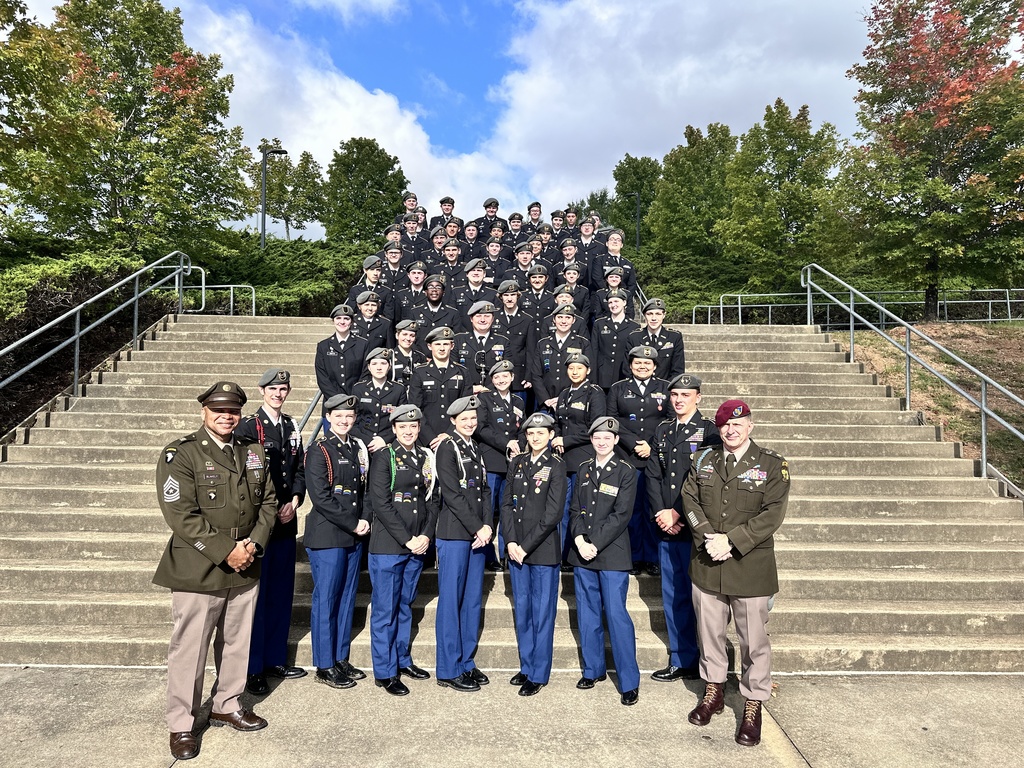 Two men in military units and a JROTC cadet battalion pose for a photo.