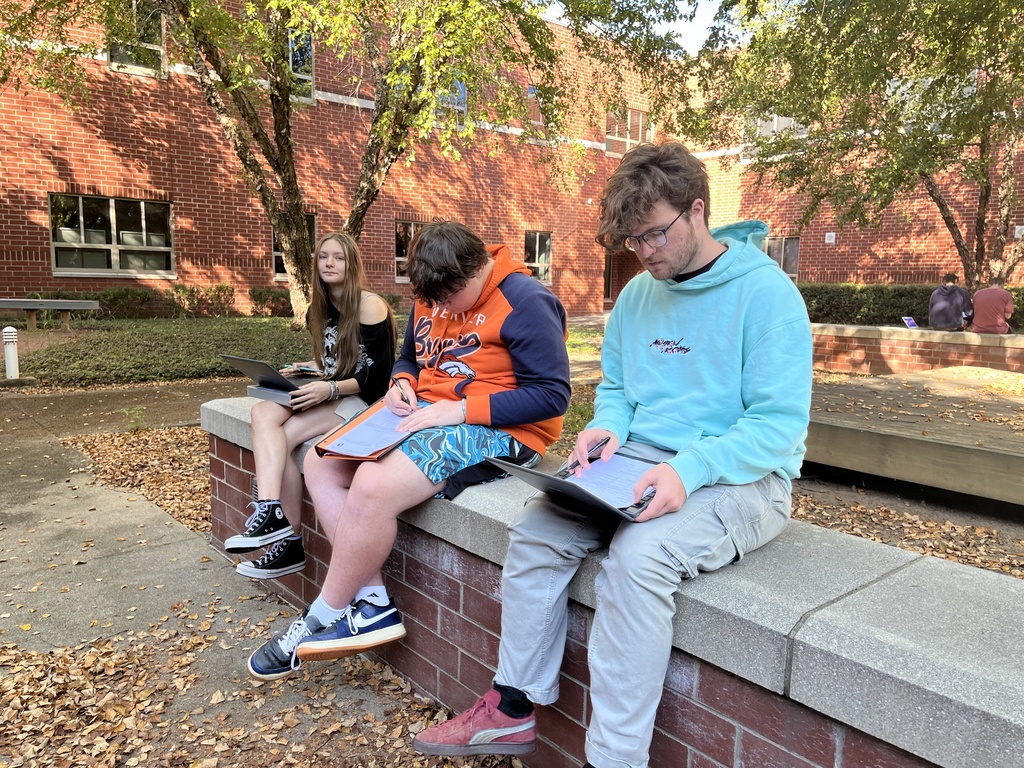 Students working outdoors in a courtyard work on a study guide.