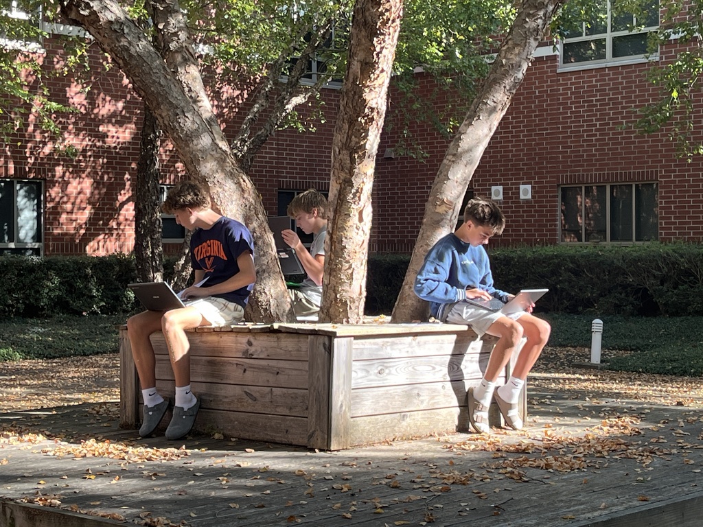 Students working outdoors in a courtyard work on a study guide.