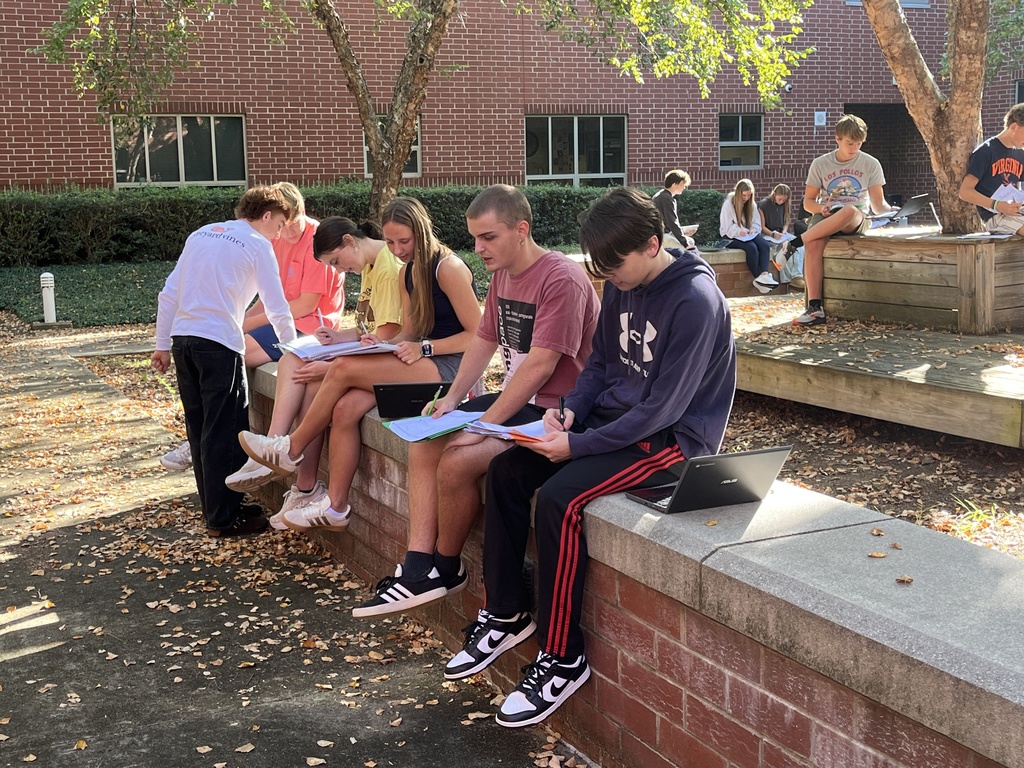 Students working outdoors in a courtyard work on a study guide.