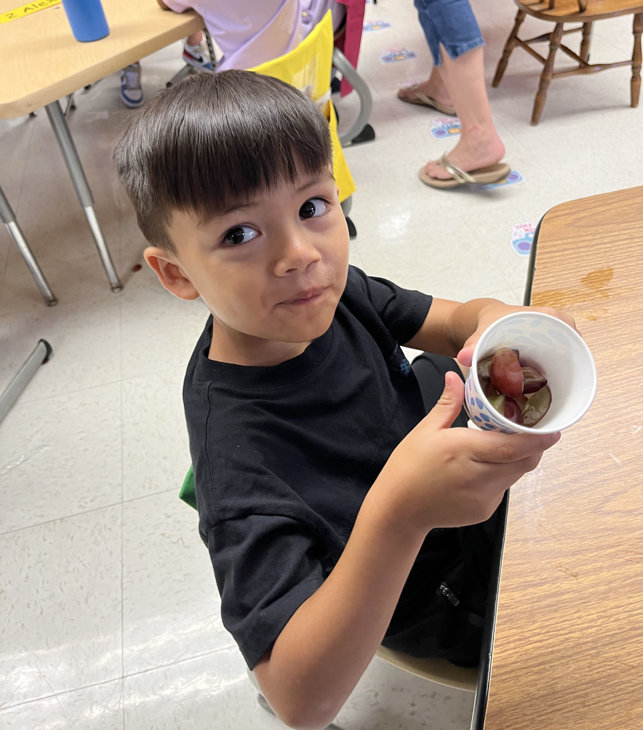 A preschooler enjoys grapes as the snack for purple day.