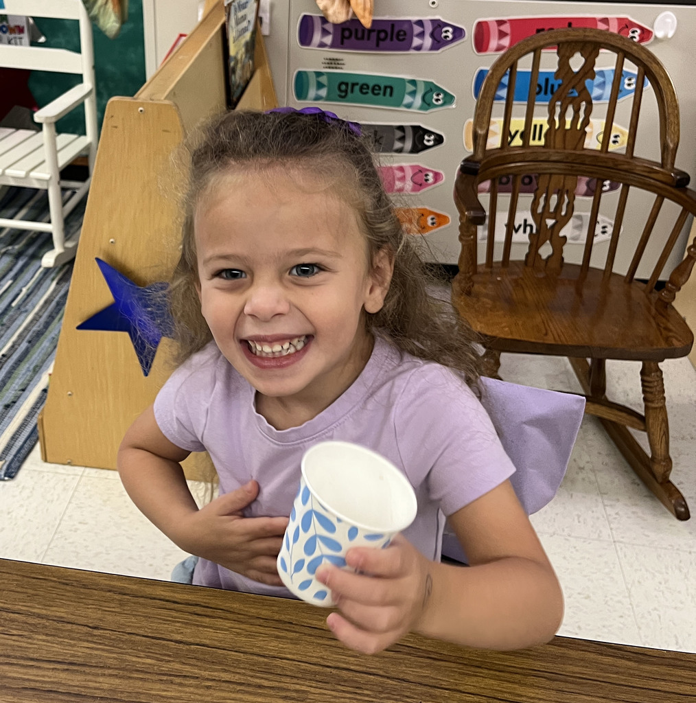 A preschooler enjoys grapes as the snack for purple day.