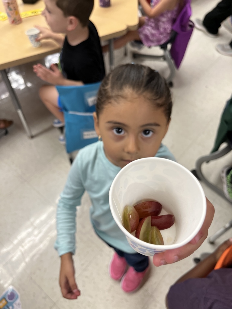 A preschooler enjoys grapes as the snack for purple day.