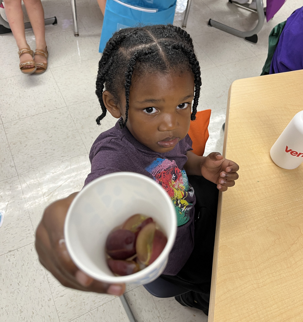 A preschooler enjoys grapes as the snack for purple day.