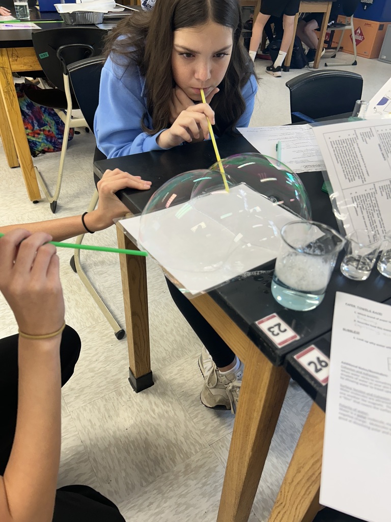 Students blow bubbles during a water experiment.