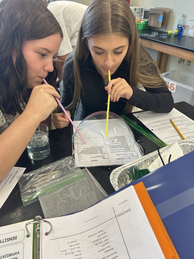 Students blow bubbles during a water experiment.