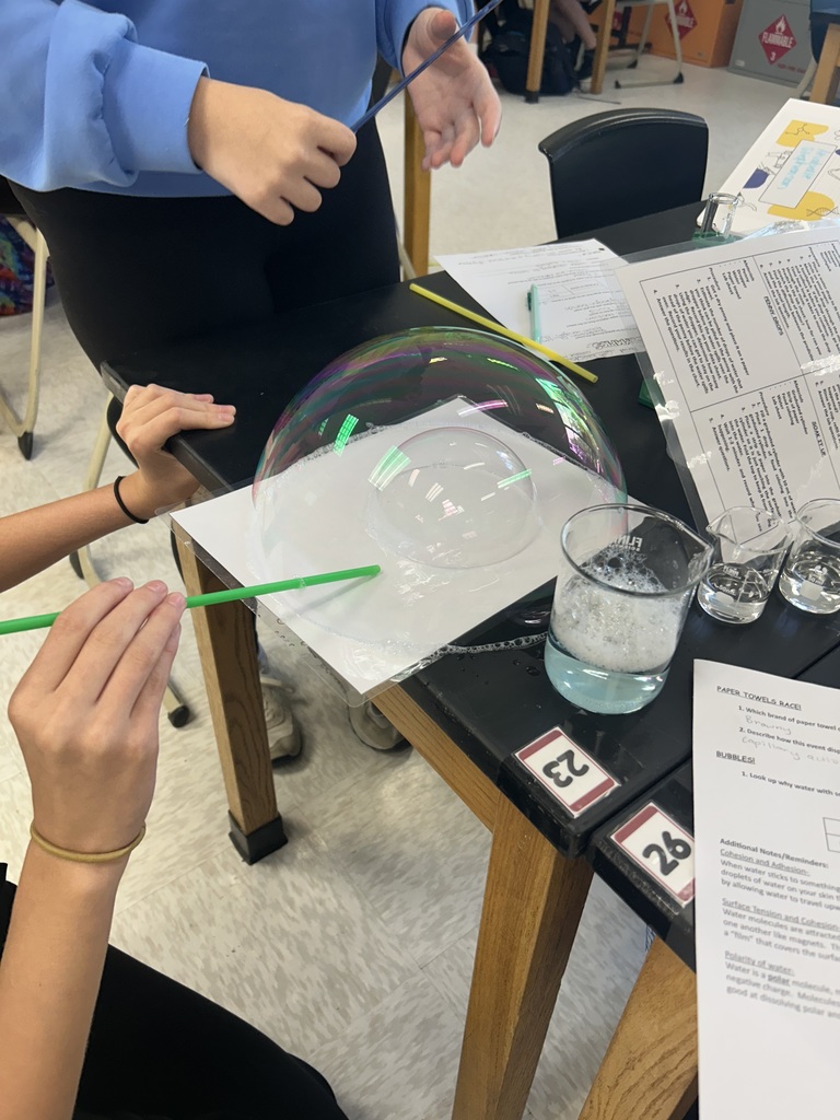 Students blow bubbles during a water experiment.
