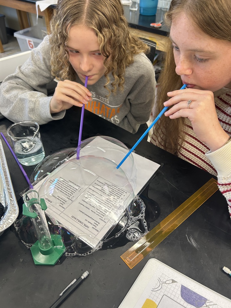 Students blow bubbles during a water experiment.