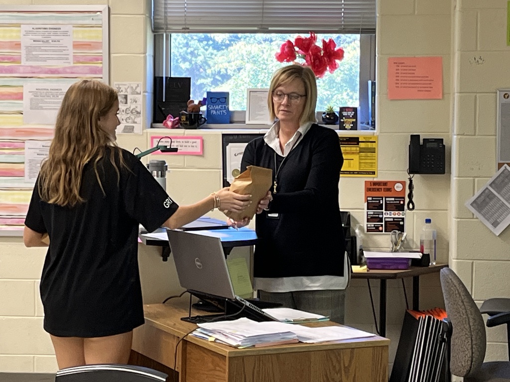 A student delivers a goodie bag to a teacher. 