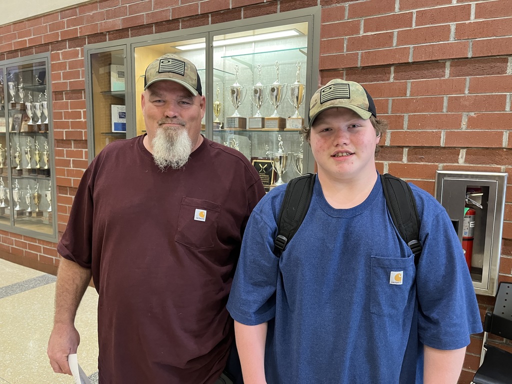 An adult and a  student pose for a photo on a back-to-school night.