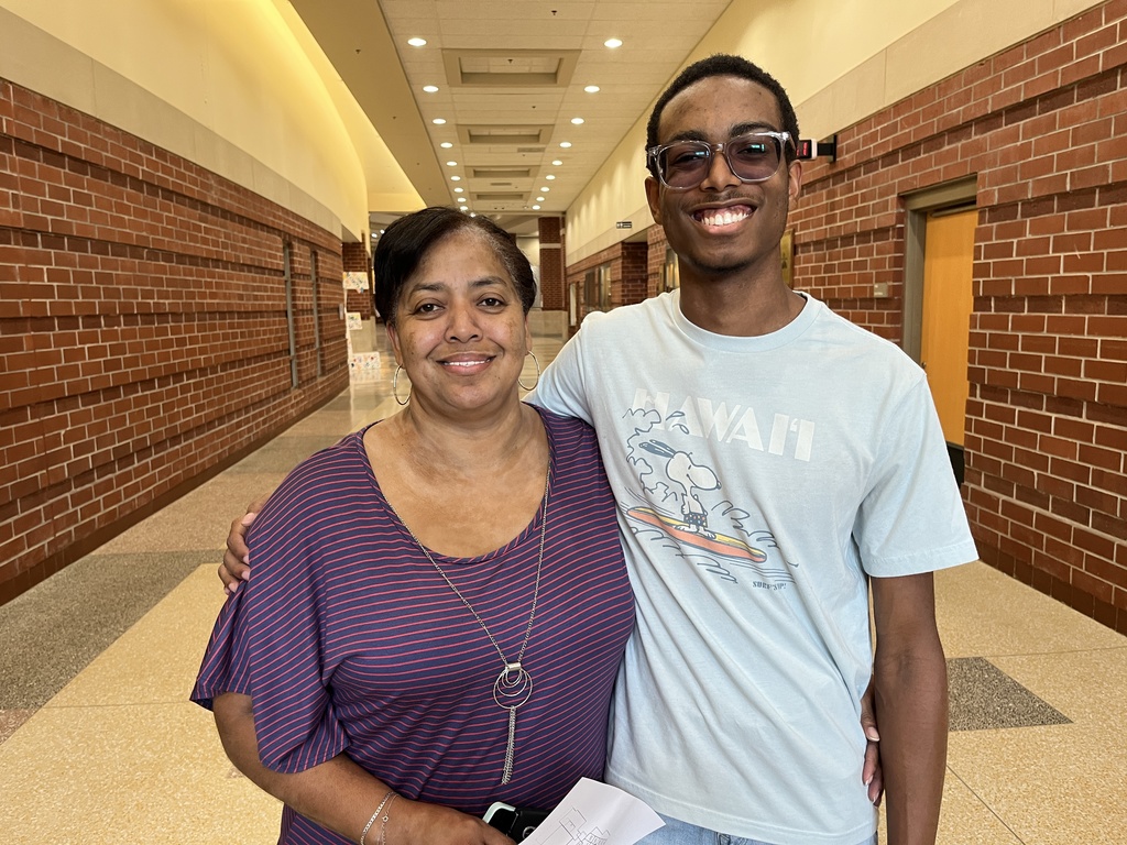 An adult and a  student pose for a photo on a back-to-school night.