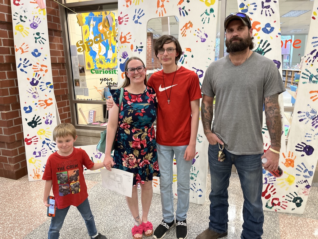 Two adults and two students pose for a photo on a back-to-school night.