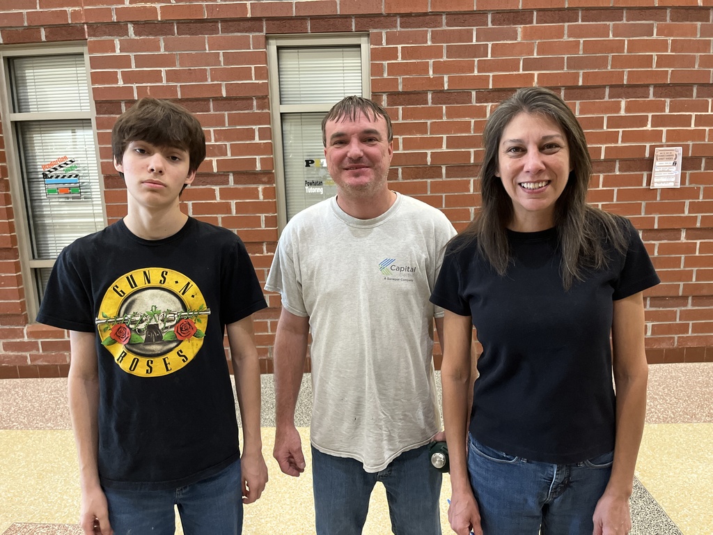 Two adults and a  student pose for a photo on a back-to-school night.